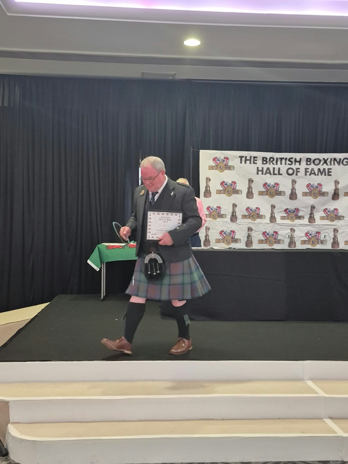 Jock McInnes MBE receiving his Hall of Fame induction certificate on stage